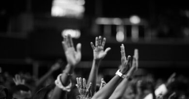 grayscale photography of people raising hands