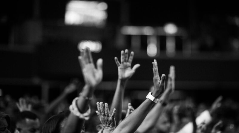grayscale photography of people raising hands