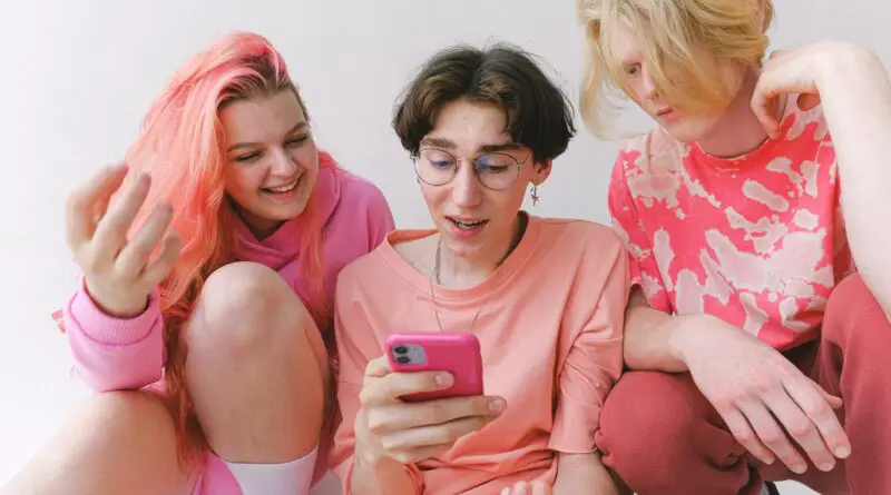 cheerful teenagers with smartphone looking at screen