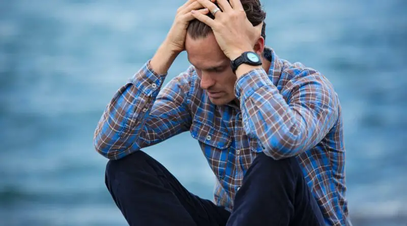 man in blue and brown plaid dress shirt touching his hair