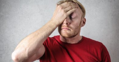 a man in red shirt covering his face
