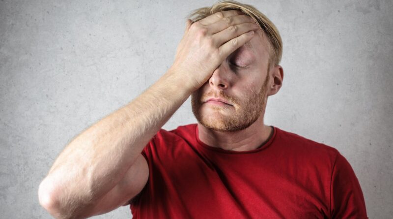 a man in red shirt covering his face