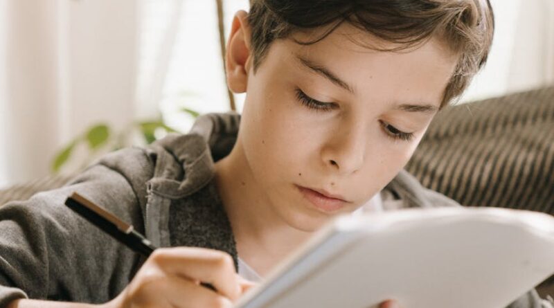 boy in gray hoodie holding white tablet computer