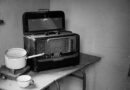 grayscale photo of vintage radio beside stove with cooking pot