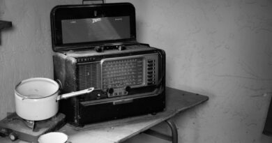 grayscale photo of vintage radio beside stove with cooking pot