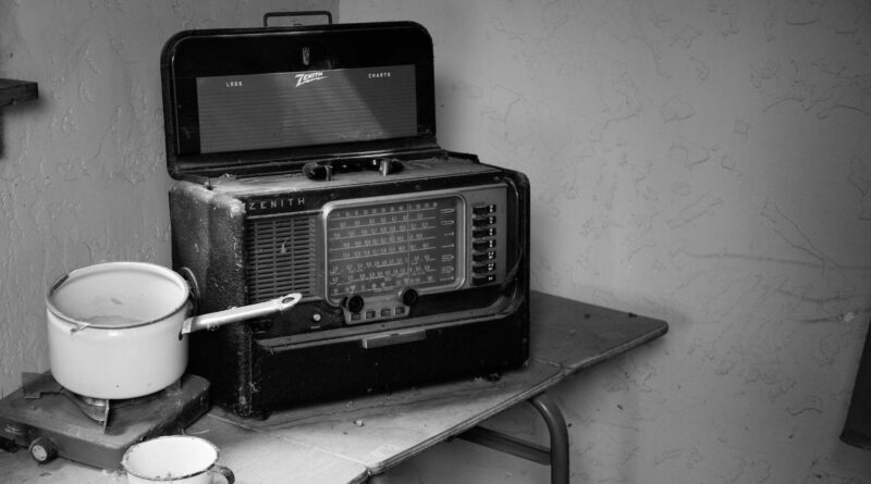 grayscale photo of vintage radio beside stove with cooking pot