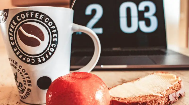 closeup photo of white and black printed ceramic mug beside pastry