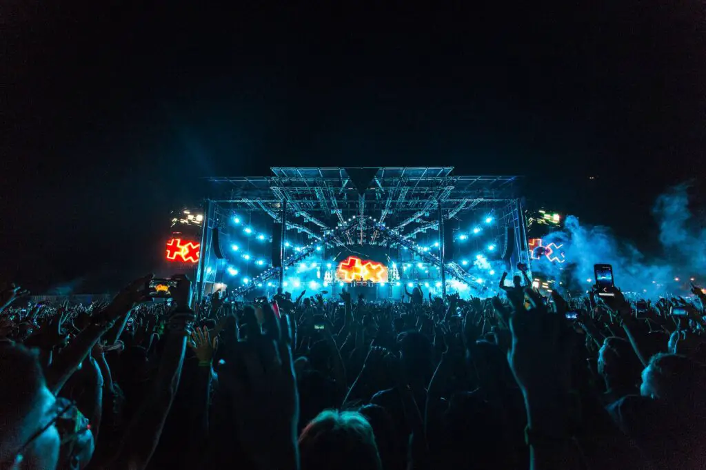 crowd in front of blue and orange stage during a concert at night