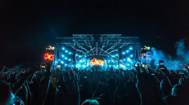 crowd in front of blue and orange stage during a concert at night